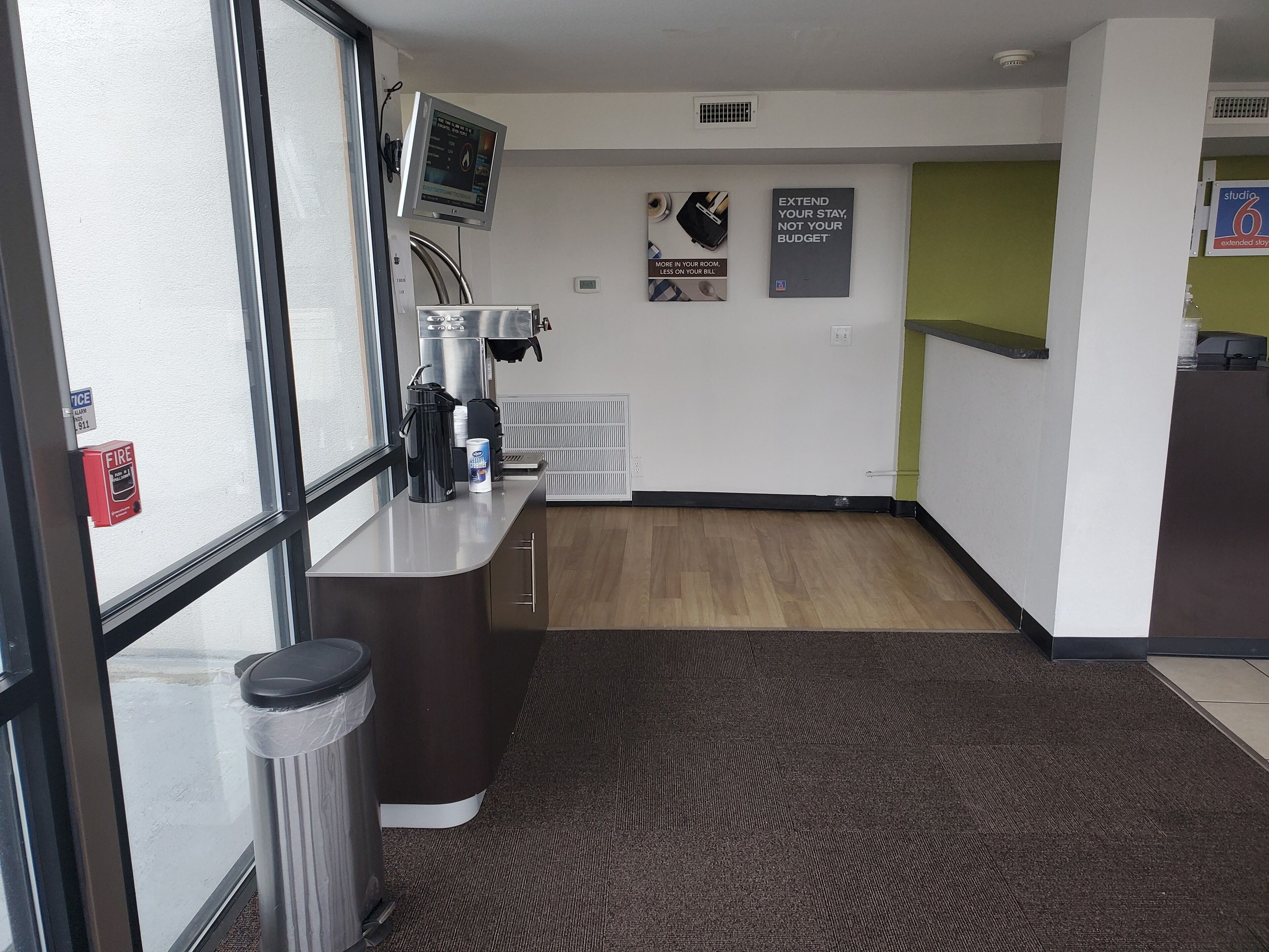 A modern office space with a reception desk, a coffee machine, a trash bin, and a poster on the wall.