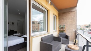 A balcony with wicker furniture, a bed, and a view of the city.