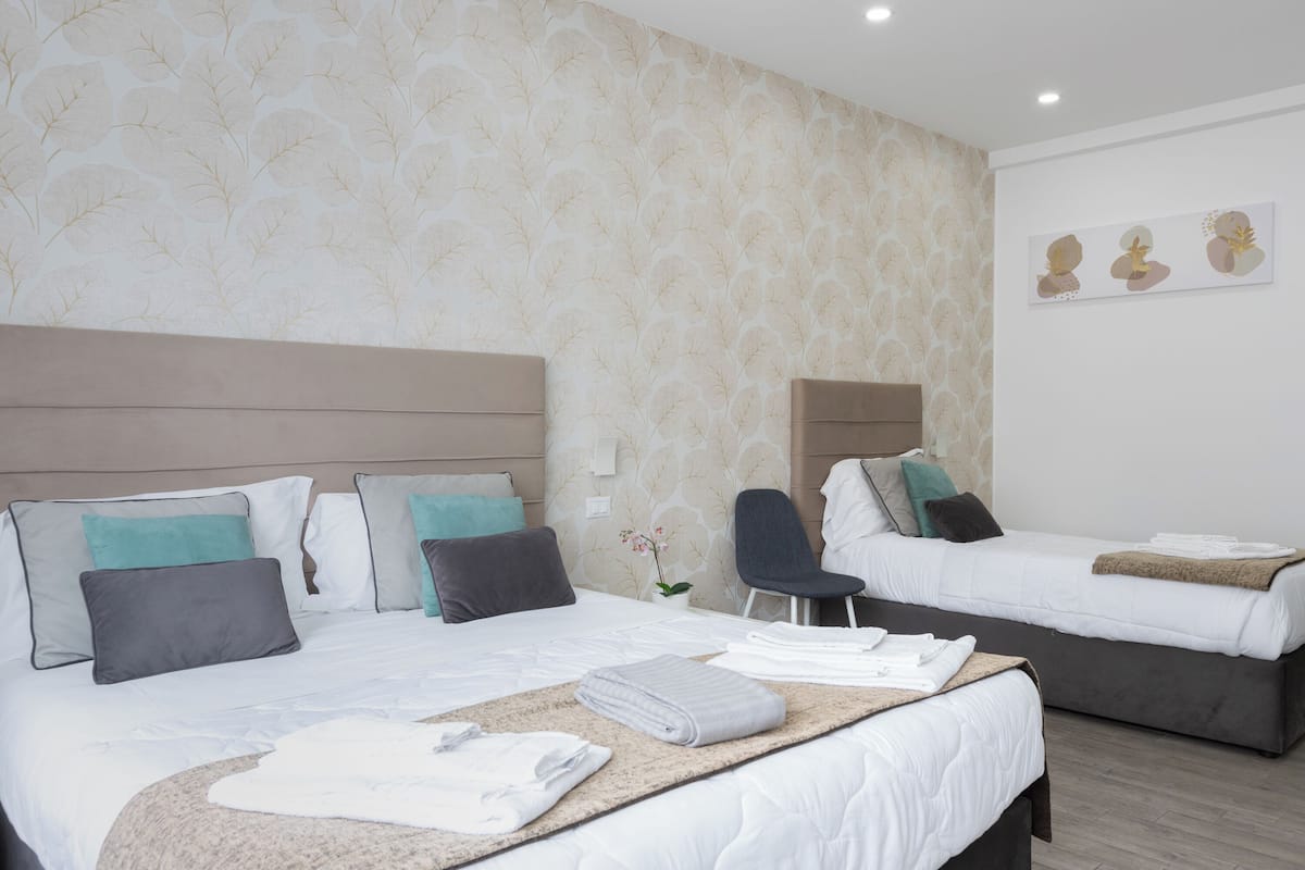 A hotel room with two beds, a sitting area, and a wall with a leaf pattern.