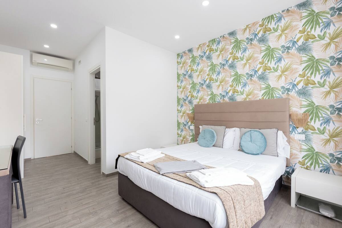 A bedroom with a bed, a desk, and a chair.