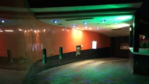 Un espacio interior tenuemente iluminado con un muro curvo y una pequeña zona de escenario.