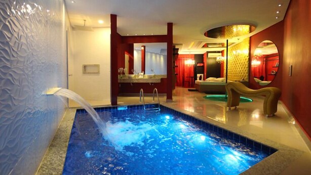 Una piscina interior moderna con una fuente de agua cristalina, una zona de estar e iluminación agradable.