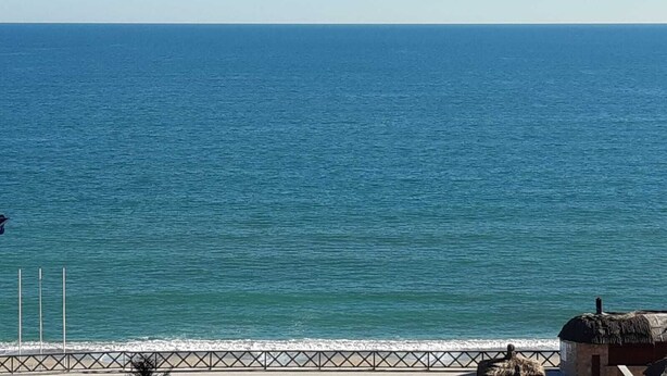 A coastal view with a clear sky, a calm sea, and a metal railing along the shore. - Igneada Meltem Hotel (Demirköy)