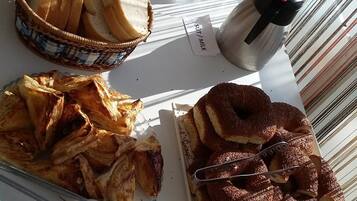 Una mesa con diversos alimentos, como pan, pasteles y un pastel de chocolate.