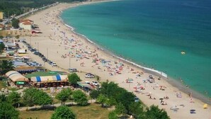 A beach with numerous umbrellas and people, a clear blue sea, and buildings along the shore. - Igneada Meltem Hotel (Demirköy)