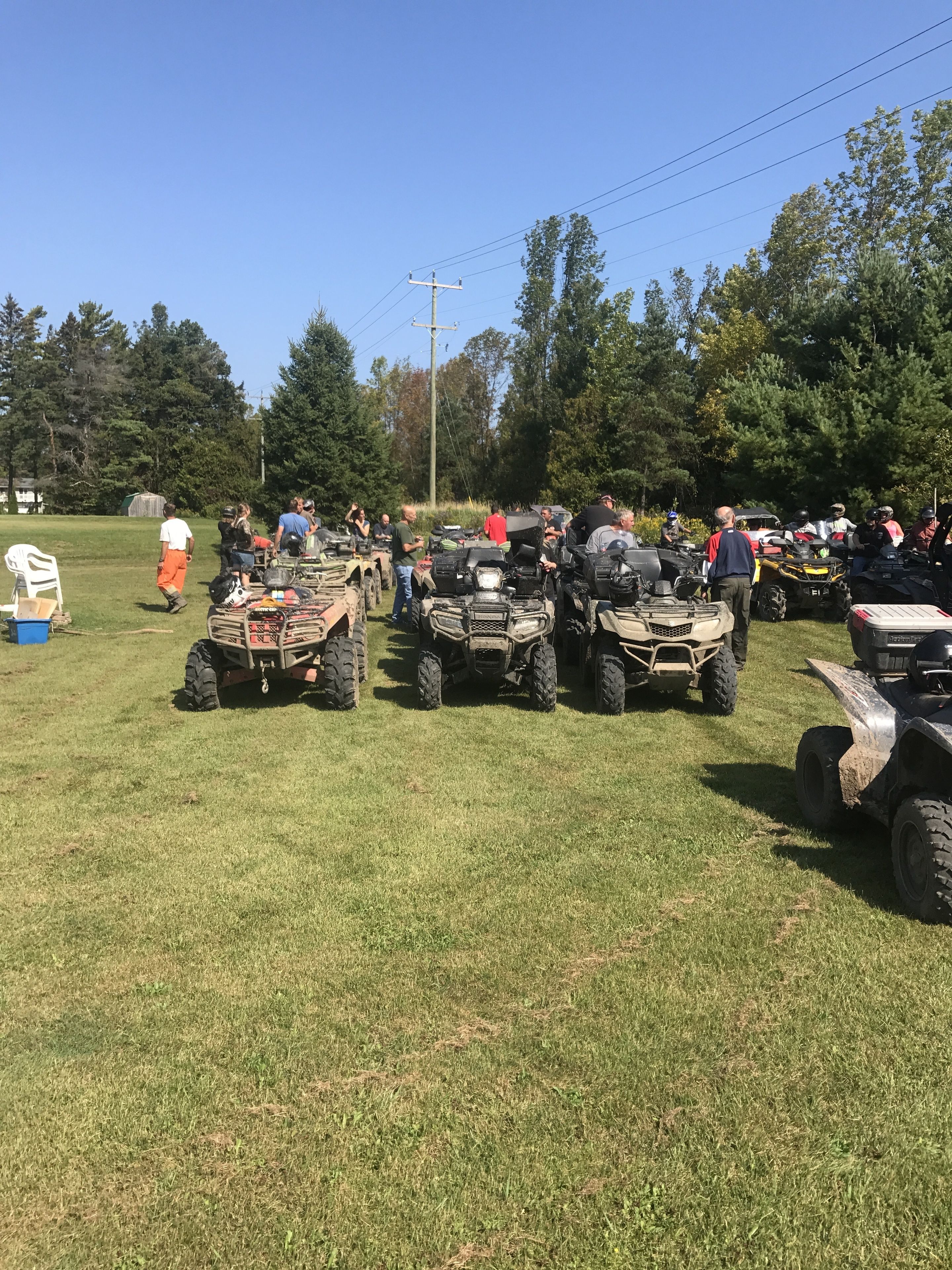 A group of ATVs parked on a grassy field with trees in the background.