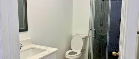 Un baño con inodoro, ducha con cerramiento de vidrio y lavamanos blanco.