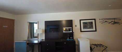 Une chambre d’hôtel avec deux lits, un bureau avec un ordinateur, un four à micro-ondes, une machine à café, une télévision et un étendoir à linge.