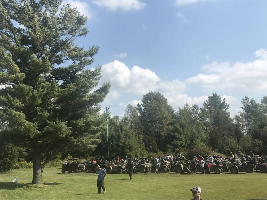 A grassy field with a large crowd of people and ATVs.