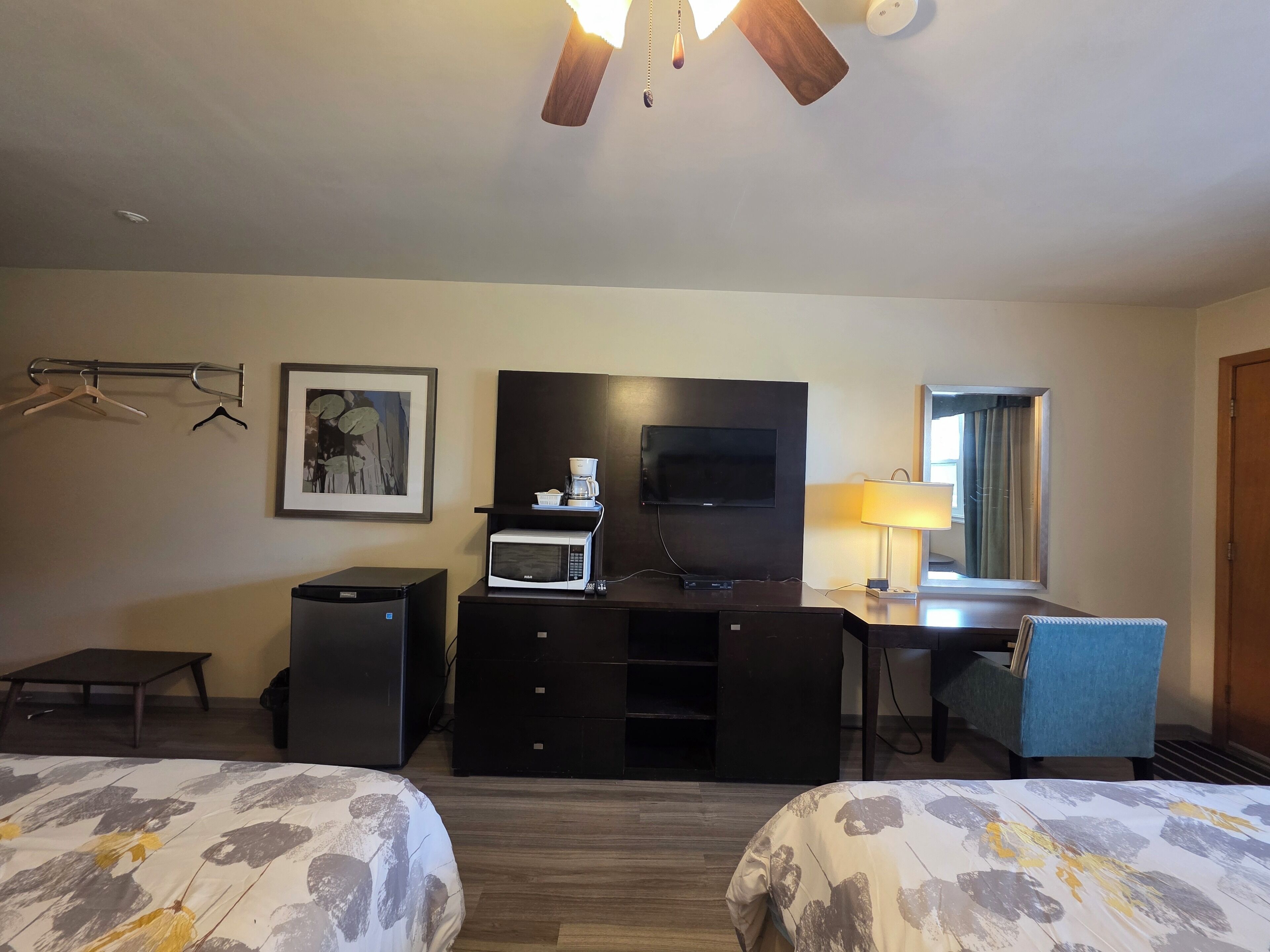 Habitación de hotel con dos camas, un escritorio, un televisor, cafetera y microondas.