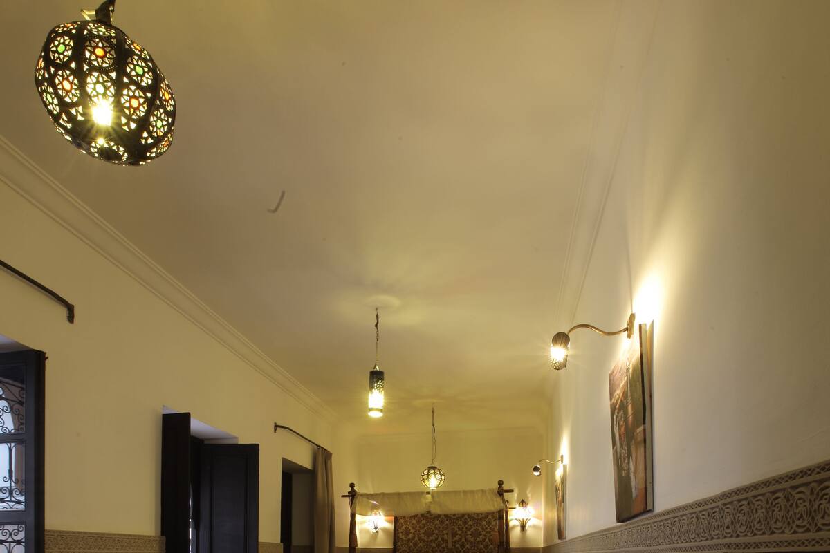 A hotel room with a bed, a sofa, a small table, and a decorative lamp.