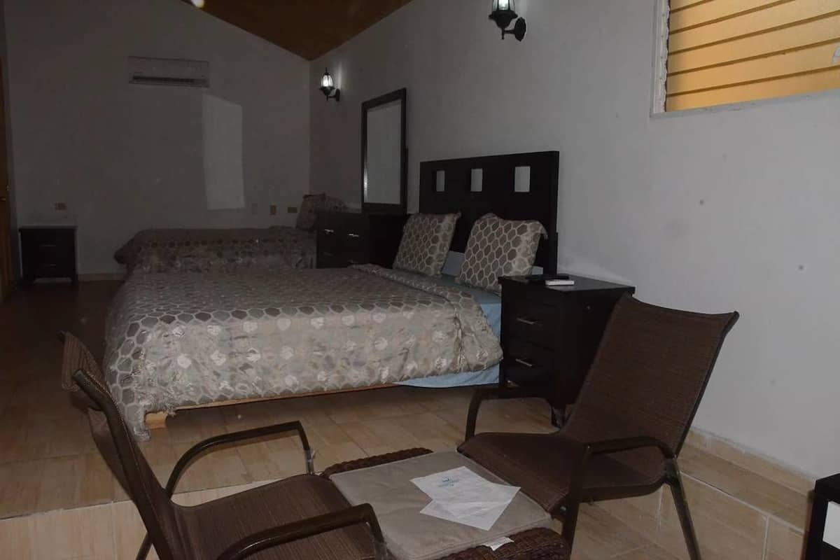 A bedroom with a bed, two nightstands, a chair, and a dresser.