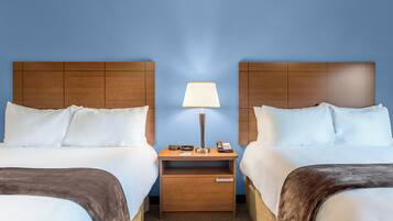 Une chambre d’hôtel avec deux lits, une table de chevet avec une lampe, un téléphone et un petit tiroir.