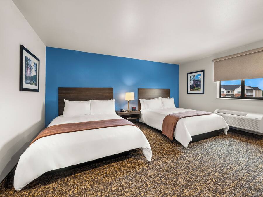 Habitación de hotel con dos camas, una pared de acento azul, un ventanal con vistas y un radiador.