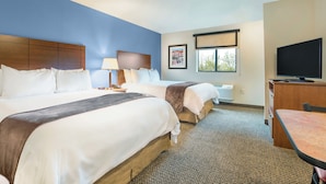 Une chambre d’hôtel avec deux lits, une télévision, un bureau et une fenêtre donnant sur un paysage agréable.