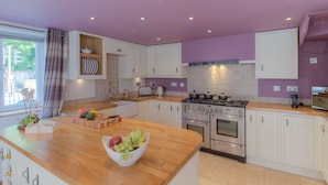 A modern kitchen with white cabinets, a wooden countertop, and a gas stove.