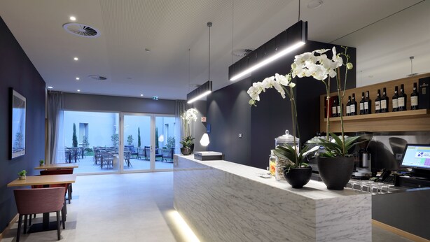 A modern reception area with a marble counter, potted plants, and a wine rack. - Eurostars Porto Centro (Porto)
