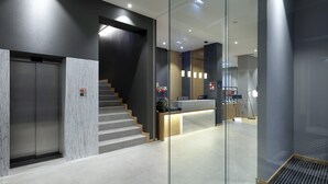 A modern reception area with a marble reception desk, a staircase, and a glass partition. - Eurostars Porto Centro (Porto)
