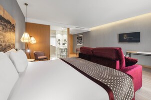 Una habitación de hotel moderna con una cama grande, un escritorio y un televisor.