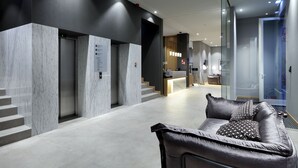 A modern lobby with a reception desk, a leather sofa, marble walls, and a staircase. - Eurostars Porto Centro (Porto)