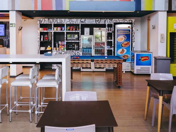 A restaurant interior with a counter, chairs, and a refrigerator.