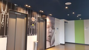 Ein Innenbereich mit Aufzügen, einem Mülleimer und einer Wand mit Hinweisschildern.