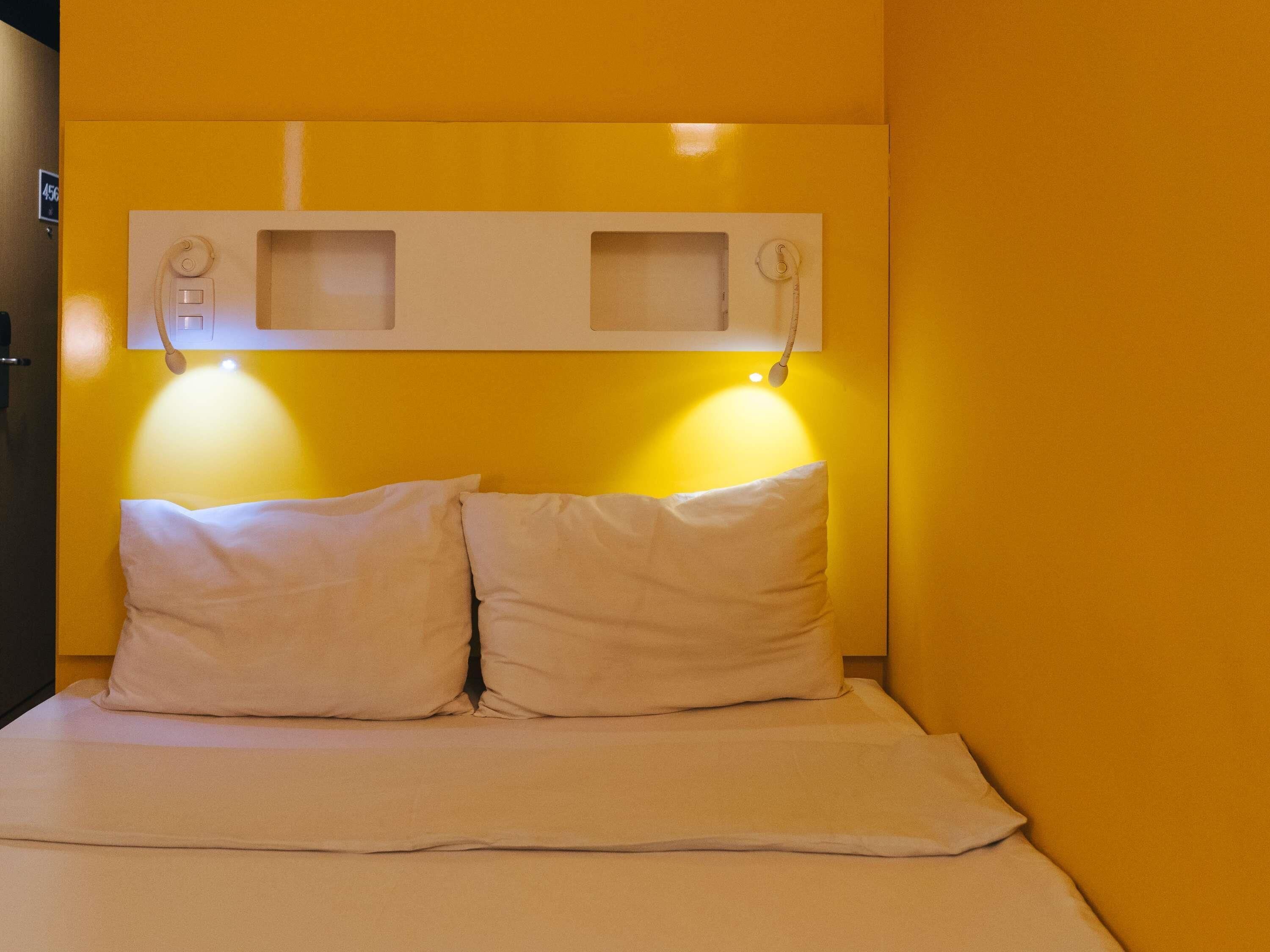 Une petite chambre avec un lit simple, deux oreillers blancs et une couvre-lit blanche.