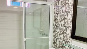 A modern bathroom with a glass shower enclosure, a toilet, a bidet, and a glass shelf. - Bahia Tropical III (San Andrés)
