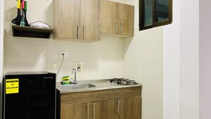 A compact kitchen with wooden cabinets, a black refrigerator, a gas stove, and a sink. - Bahia Tropical III (San Andrés)