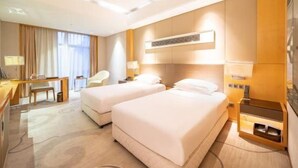 Ein Hotelzimmer mit zwei Betten, einem Schreibtisch, einem Stuhl und einem Fernseher.