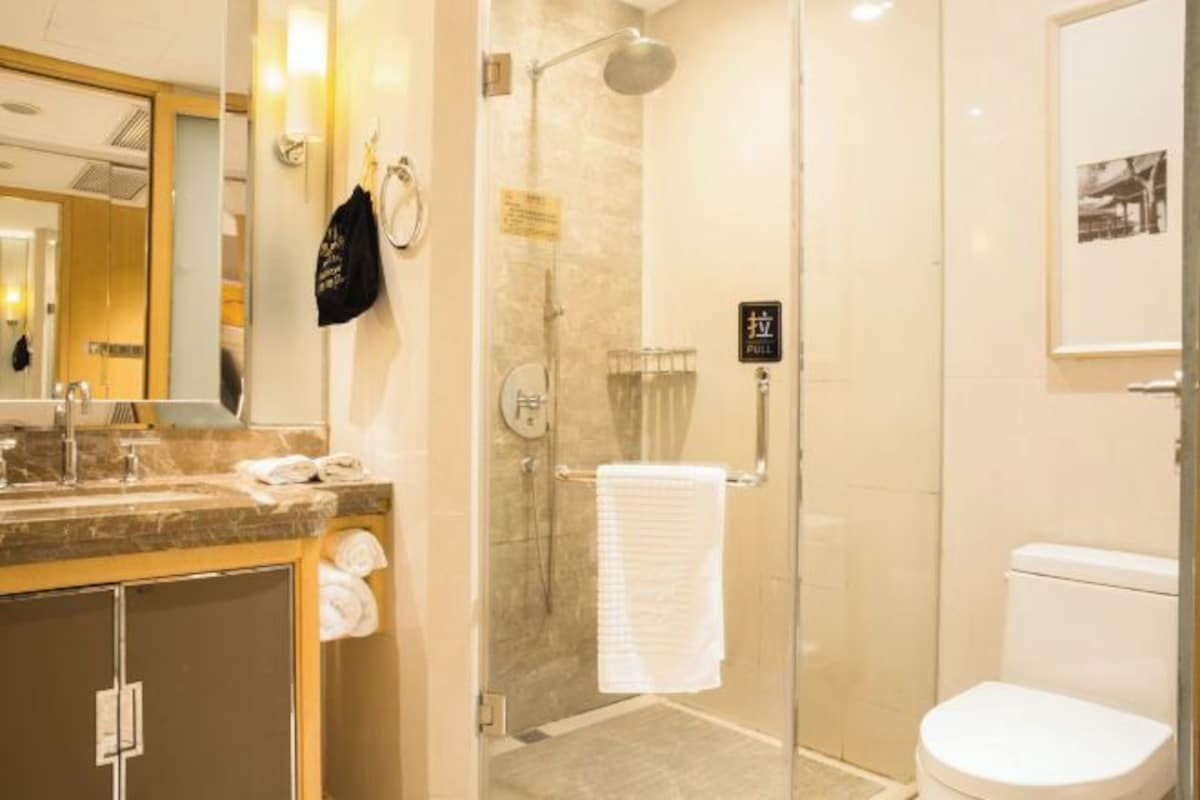 Une salle de bain moderne avec une douche à parois de verre, des toilettes blanches et un plan de toilette en marbre avec un lavabo.