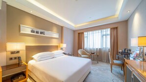 Ein Hotelzimmer mit einem großen Bett, Nachttischen, einem Schreibtisch und einem Sessel.