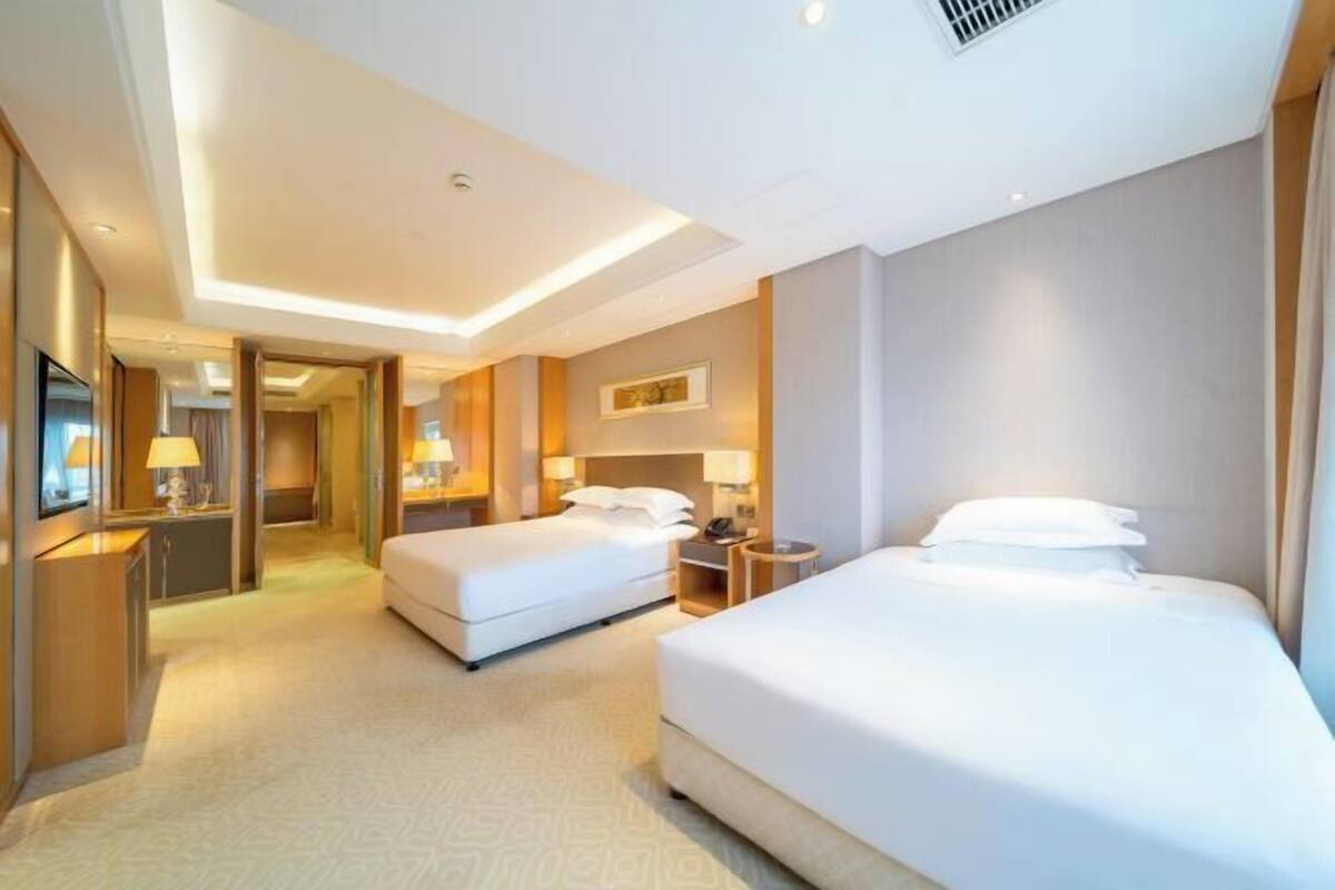 A hotel room with two beds, a desk, and a television.
