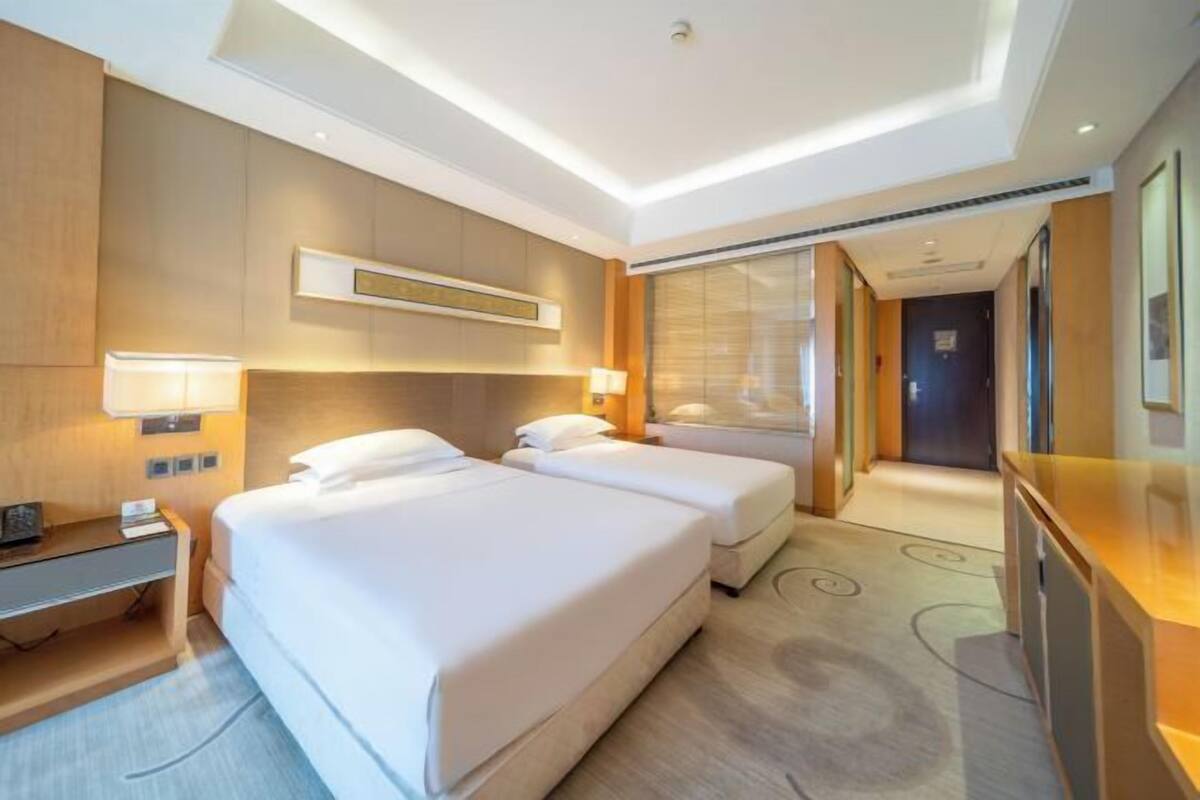 A hotel room with two beds, a desk, and a large mirror.
