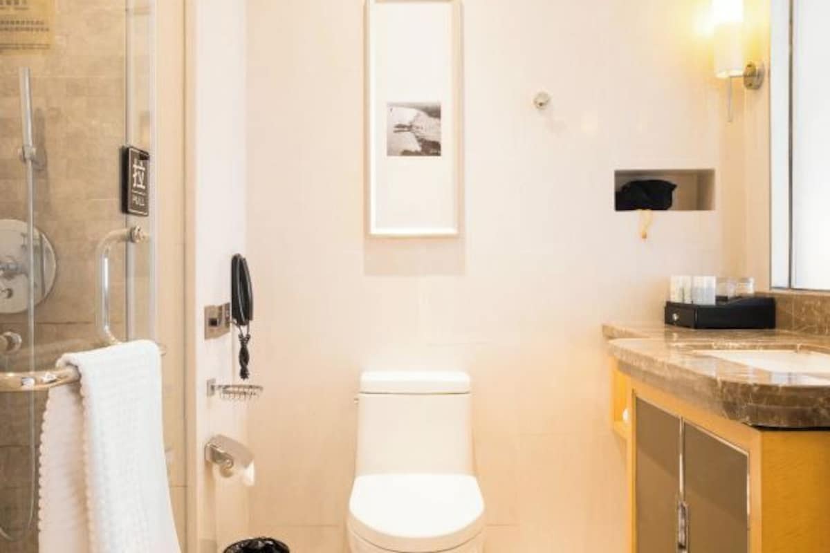 Une salle de bain moderne avec une douche à l’italienne en verre, des toilettes blanches et un comptoir en marbre.