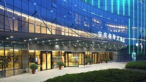 A modern hotel with a glass facade, a curved entrance, and a well-lit exterior. - Nanxiang Hotel (Anqing)