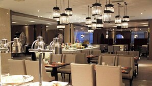 A modern dining area with multiple tables and chairs, ambient lighting, and a bar in the background. - Nanxiang Hotel (Anqing)