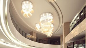 A modern interior with curved balconies and multiple chandeliers. - Nanxiang Hotel (Anqing)