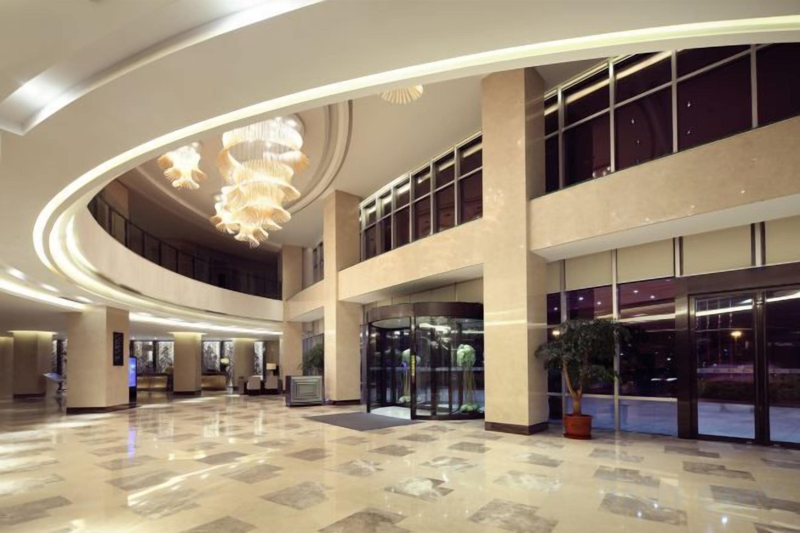 A spacious lobby with a high ceiling, large windows, and a central chandelier.