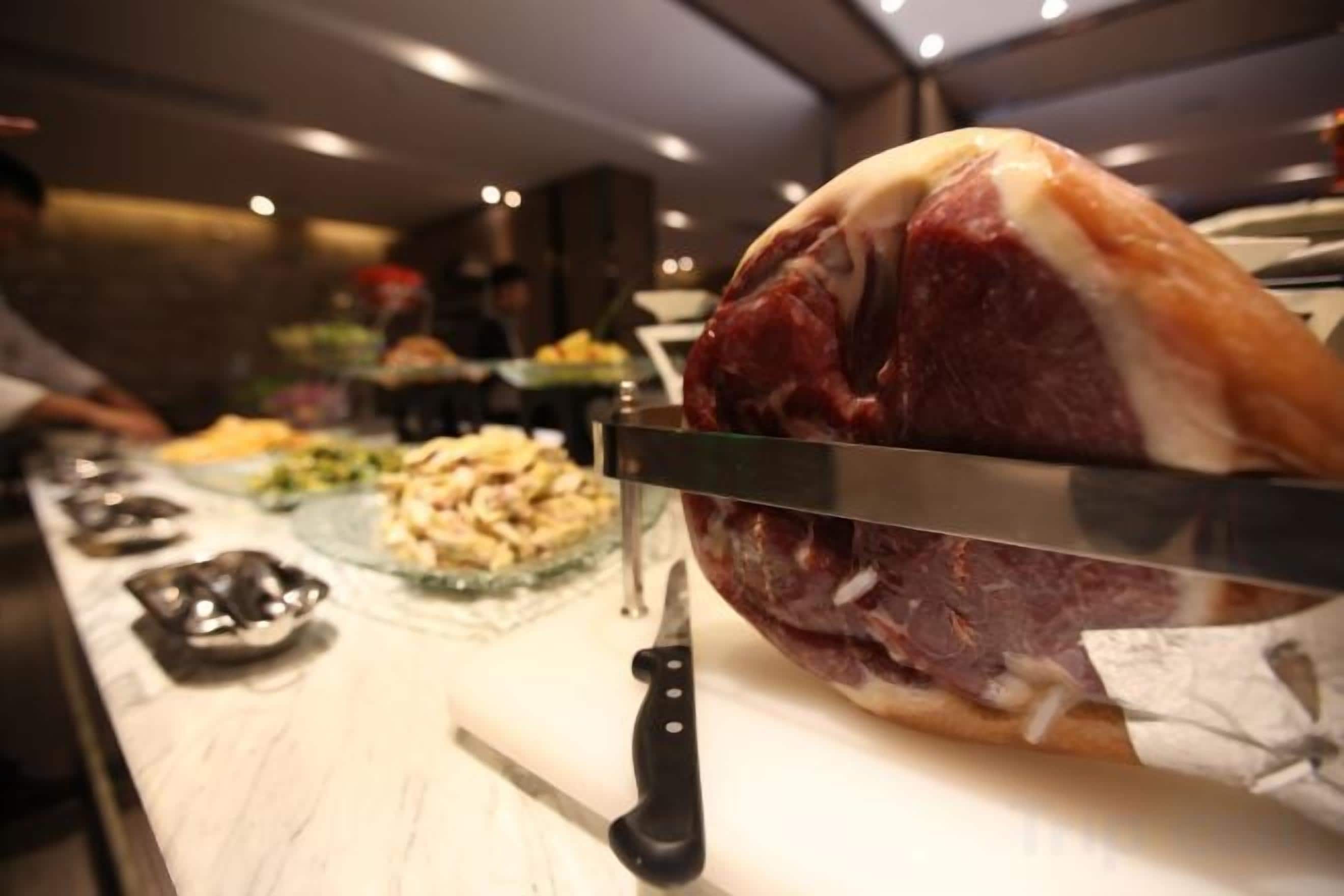A large piece of meat being sliced with a knife on a counter.