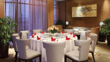 A dining area with round tables, chairs, and a central floral arrangement.