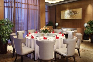 A dining area with round tables, chairs, and a central floral arrangement. - Nanxiang Hotel (Anqing)