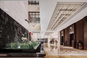 A hotel lobby with a marble floor, a black wall with a decorative element, and a ceiling with a grid pattern. - Yancheng Guest Hotel (Yancheng City)