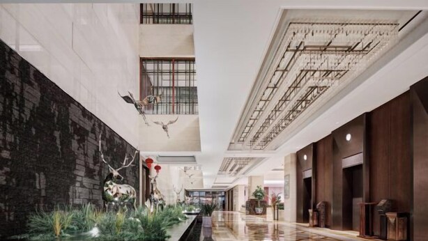 Eine großzügige Lobby mit Marmorboden, einer Wand aus schwarzem Stein und einer dekorativen Wasserspielen mit Geweihen.