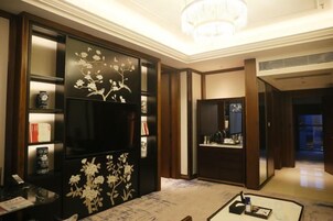 Habitación de hotel con un mueble negro grande decorado con motivos florales, un candelabro y un espejo.