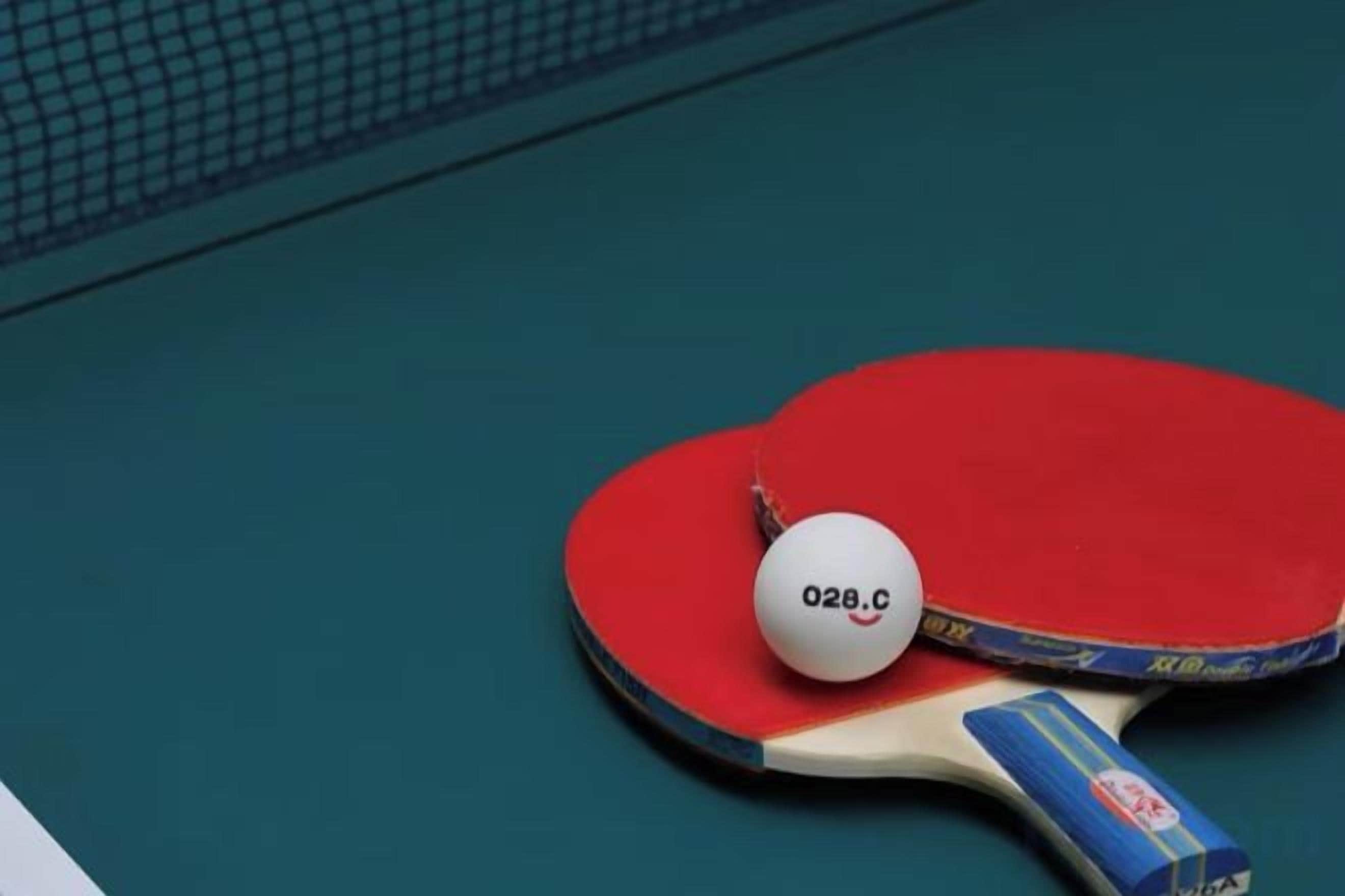 A table tennis table with a red paddle and a ball marked '028.C'.