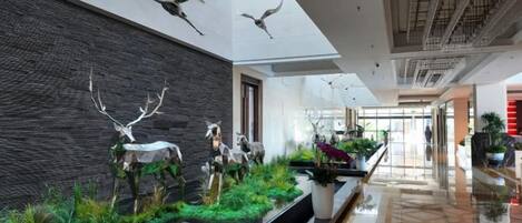 A modern lobby with a black wall, antler sculptures, and a reflective floor.