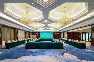 Un salón de conferencias con una larga mesa, varias sillas y una pantalla grande.