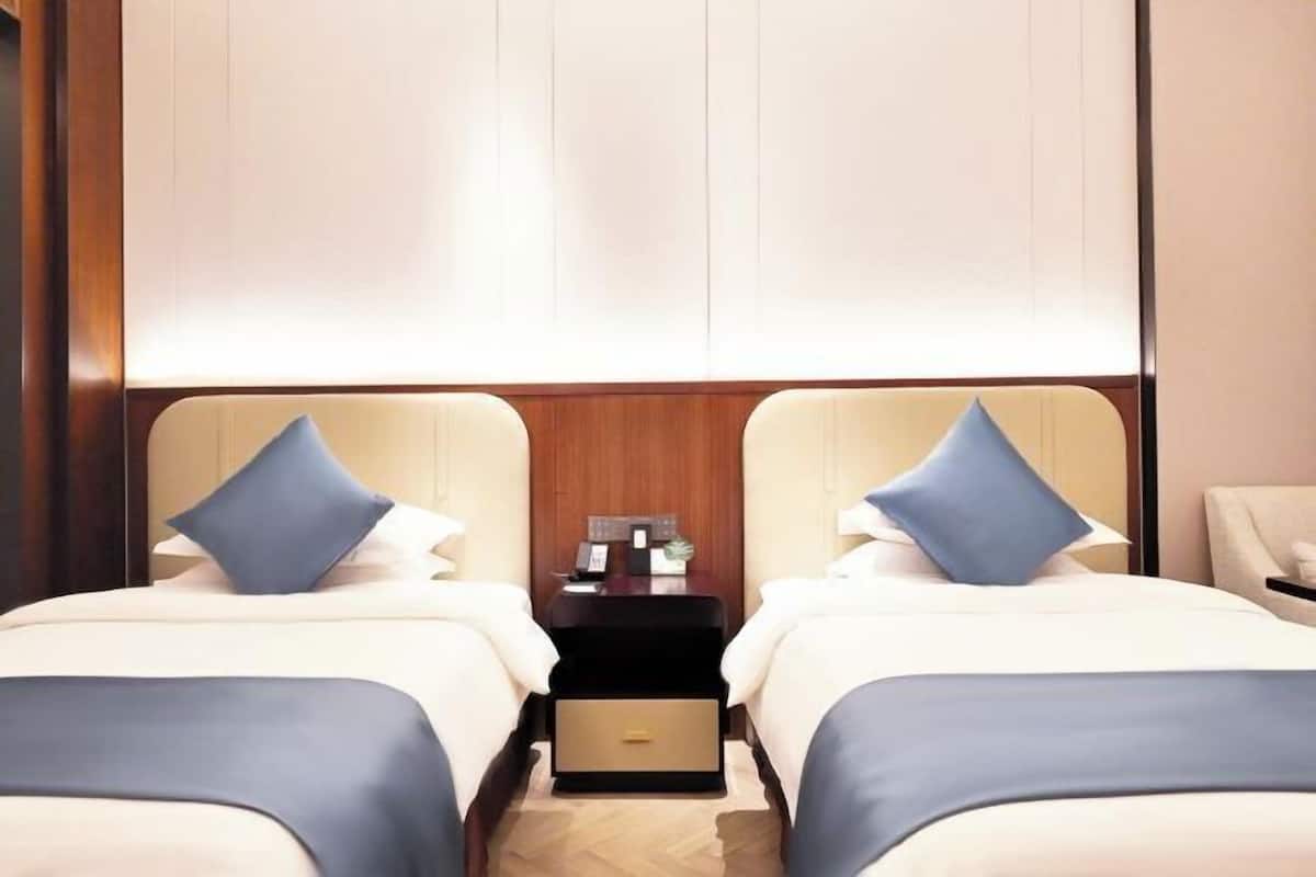Ein Hotelzimmer mit zwei Betten, einem Nachttisch und einem kleinen Schreibtisch mit Lampe.