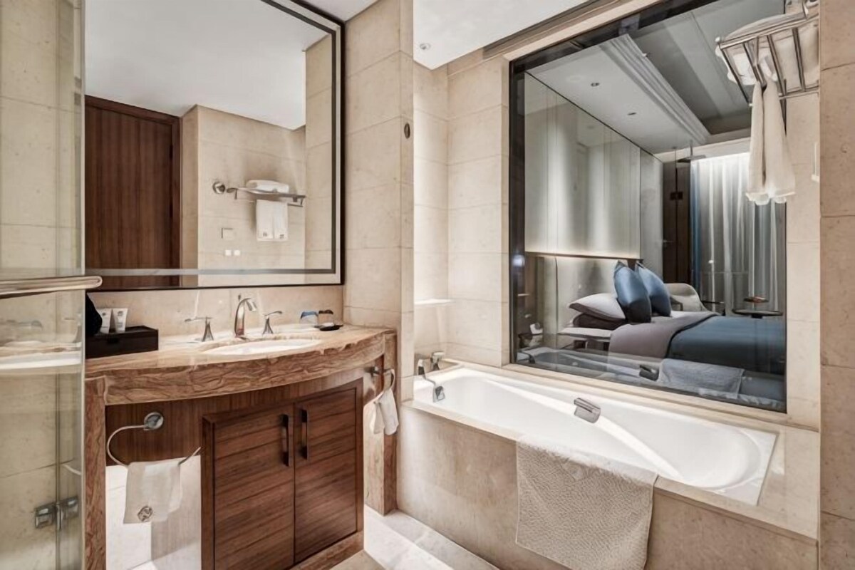 A modern bathroom with a large mirror, a bathtub, and a vanity with a sink.